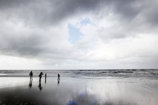 family of four having fun at the beach on a cloudy day