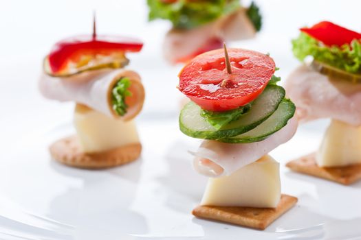 food theme: cracker with ham, cheese and vegetables on the plate