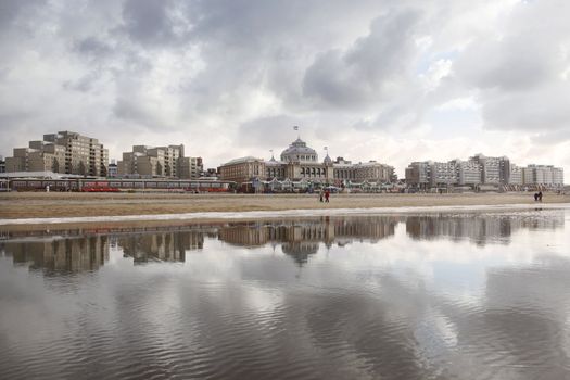 Kurhaus of Scheveningen reflected in sea water with cloudy sky