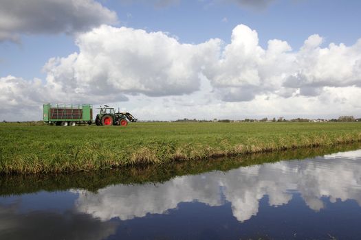 tractor in meadow and clouds reflected in canal







trac