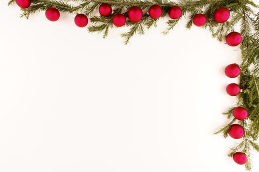 Border of red christmas garland with baubles and ribbons on white.