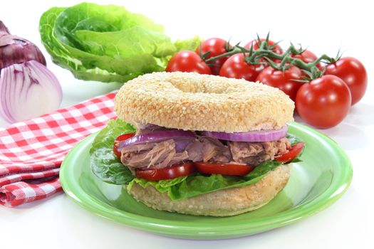 a Bagel topped with tuna, onion and tomato
