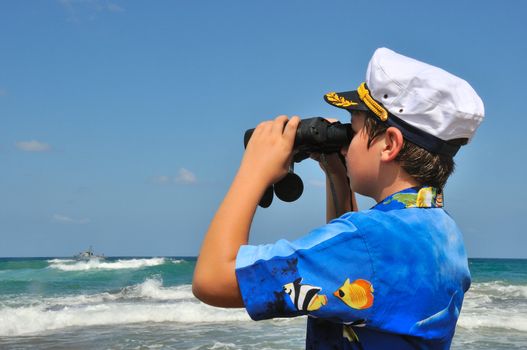 The Boy in the naval cap, considering the ship with binoculars who sailed to sea
