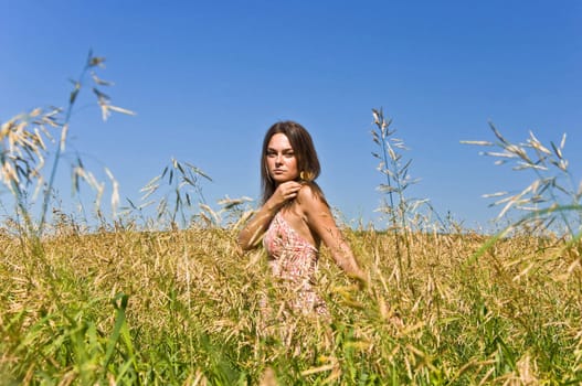 Beautiful young woman in a field of rye. Touch the ears harvest by hand. Rural landscape.