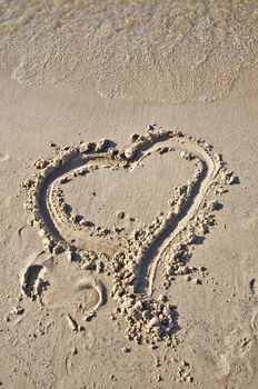 Sign of the heart in the sand. Tidal wave comes to the beach. Concept feeling.