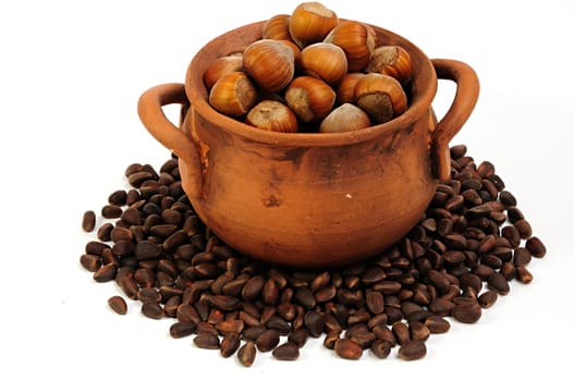 pot with hazelnuts, pine nuts surrounded, isolated, close-up