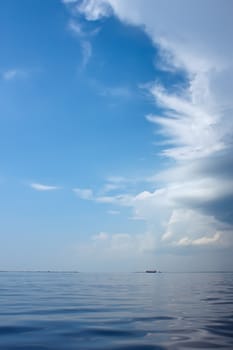 Cloudscape over the sea near the coast. Big ship sailing on the horizon