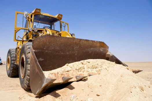 Tractor lifting sand on a desert