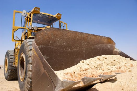Tractor lifting sand on a desert