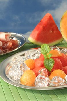 colored melon balls with ham, ice cubes and lemon balm