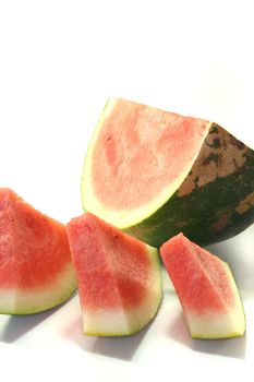 Watermelon quartered with individual slices on white background