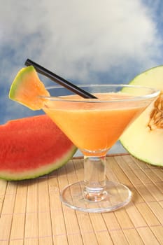 a glass of melon smoothie with cantaloupe melon pieces