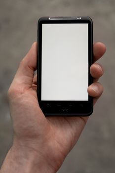 A man's hand holding mobile smartphone showing white blank screen.