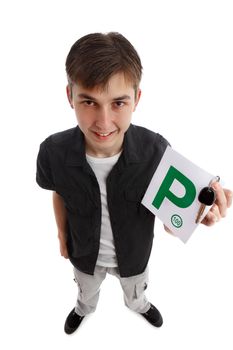 A teenage boy holds green P license plates and car key.  He is smiling enthusiastically.  Above view perspective.  Standing on a white background with slight shadows under feet.