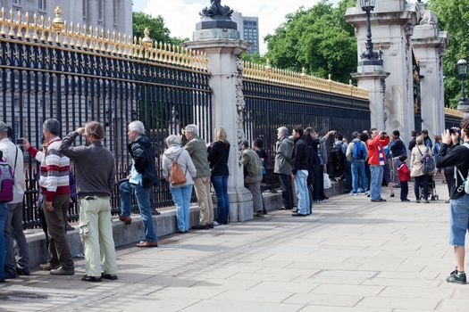 LONDON - JUNE 6: Tourists watch the Royal Guards through fence of the Buckingham Palace on June 6, 2011 in London, UK. Buckingham Palace is the principal residence and office of the British monarch and one of most popular attraction for visitors in London.