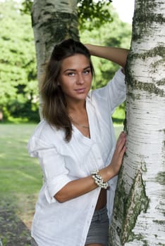Cute girl in a white shirt standing near the birches