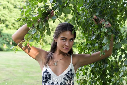 Cute girl in a white shirt standing near the birches