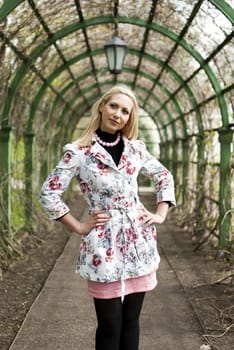 blonde girl standing in an alley in the park in summer