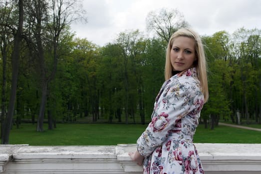 blonde girl standing against a background of park, portrait