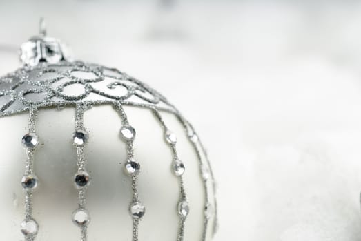 Silver christmas bauble with crystals surrounded by fluffy snow
