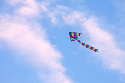 multicolored striped kite flying in the blue sky