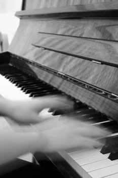 A person playing the piano with motion-blurred hands to mimic fast movement.