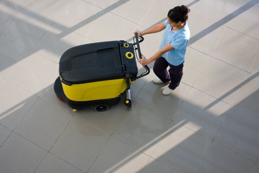 A worker is cleaning the floor with equipment