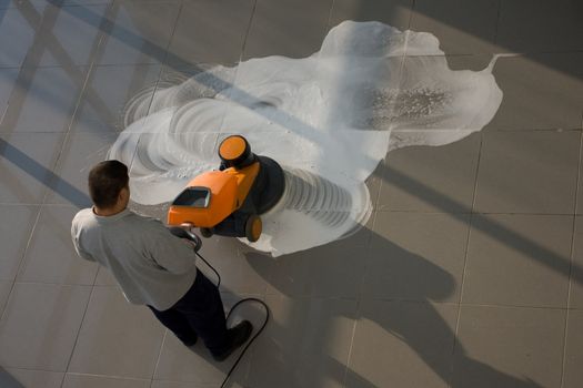 A worker is cleaning the floor with equipment