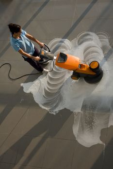 A worker is cleaning the floor with equipment