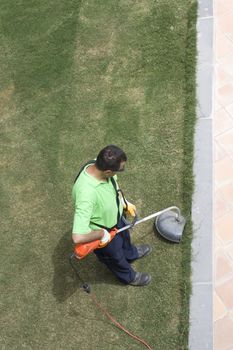 A gardener is cutting grass with machine