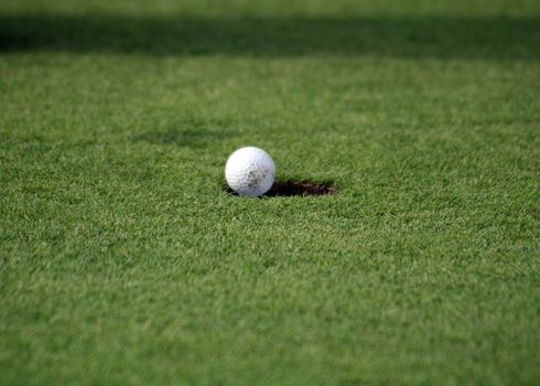 Close view of a golf ball just falling in the hole