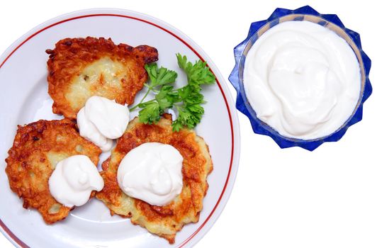 potato pancakes on plate with sour cream isolated on white