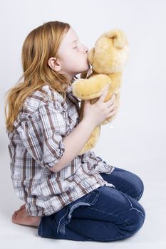 happy little girl gives her teddy bear a big kiss