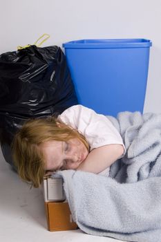 homeless kid sleeping in a box surrounded by trash