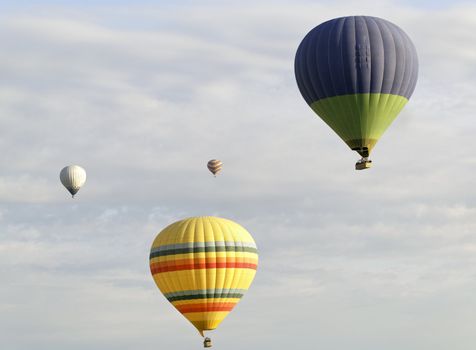 horizontal landscape of four hot air balloons amongst a cloudy sky backdrop. Horizontal, crop area, copy space