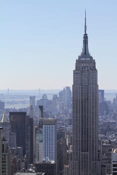 The Empire State Building with downtown Manhattan and Verrazano-Narrows Bridge in the background on hazy morning in New York City.