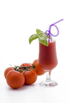 Glass of tomato juice with basil and bunch of tomatos