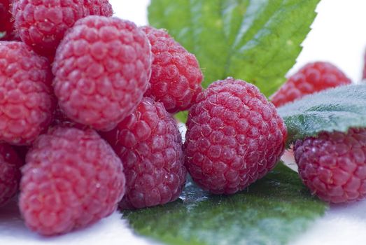 Fresh raspberries with green leaves on the white bacground