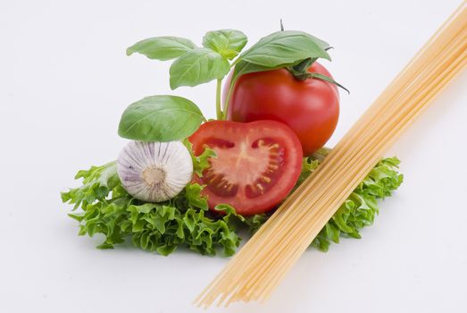 Pasta, tomatoes, balil and garlic on white background