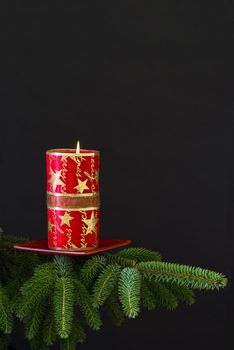 Red christmas candle on spruce branch - black background
