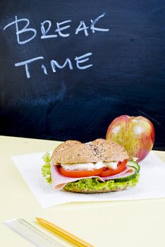 Sandwich and apple on classroom table - breakfast