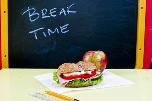 Sandwich and apple on classroom table - breakfast