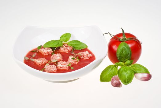 Bowl of tomato soup with tomato, basil and garlic over  white background