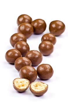 Dark brown chocolate balls and half with crisp filling over white background