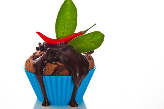 Hot chocolate cupcake with liquid chocolate and a red chili as a studio shooting