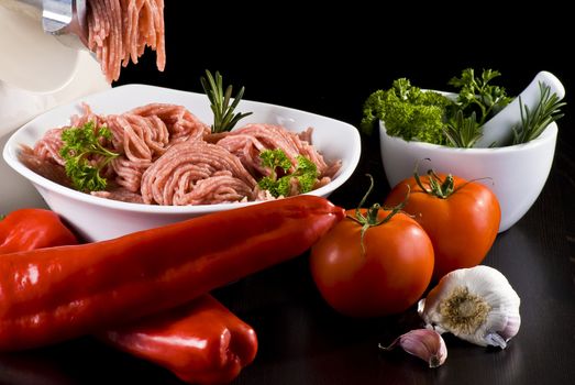 Bowl of mince with electric meat grinder and vegetables