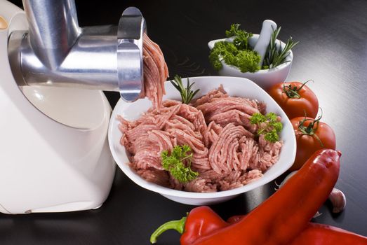 Bowl of mince with electric meat grinder and vegetables