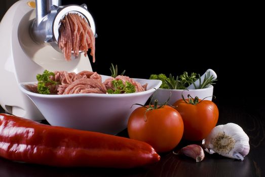 Bowl of mince with electric meat grinder and vegetables