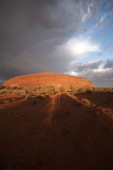 Storm clouds and rainbow over Ayers Rock (Uluru) in the Northern Territory of Australia