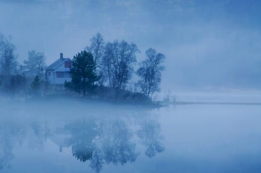 Late evening and the fog is surrounding a house. Reflections in the water